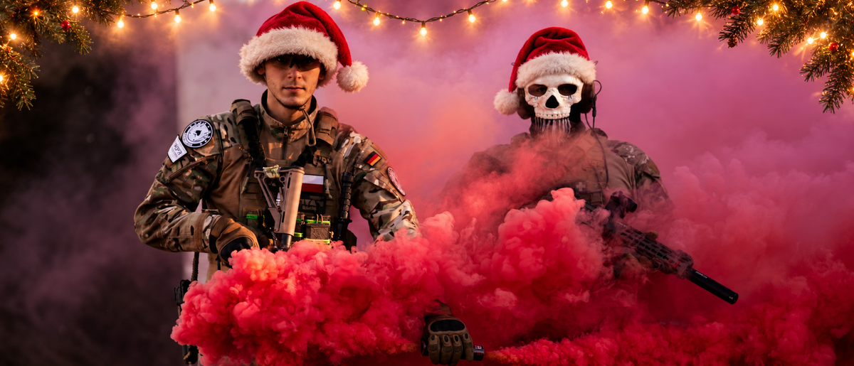Airsoft-Spieler vor rotem Rauch mit Weihnachtsmützen