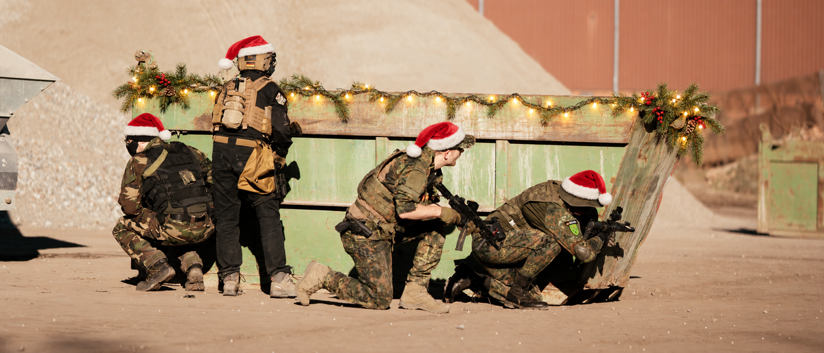 Airsoft-Team mit Weihnachtsmützen am Spielfeld